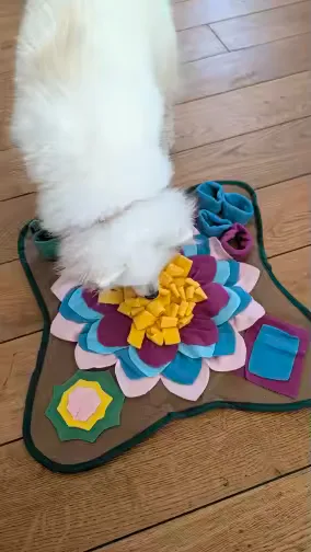 Buyer photo: a white cat digging into the Earth brown snuffle mat on a wood floor