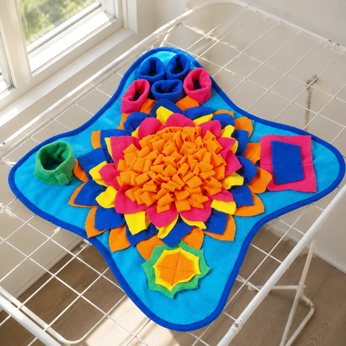 The Ocean snuffle mat laid flat to air-dry on a drying rack near a window after a wash